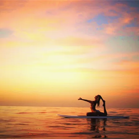 Shiva Rea in eka pada on a stand-up paddleboard