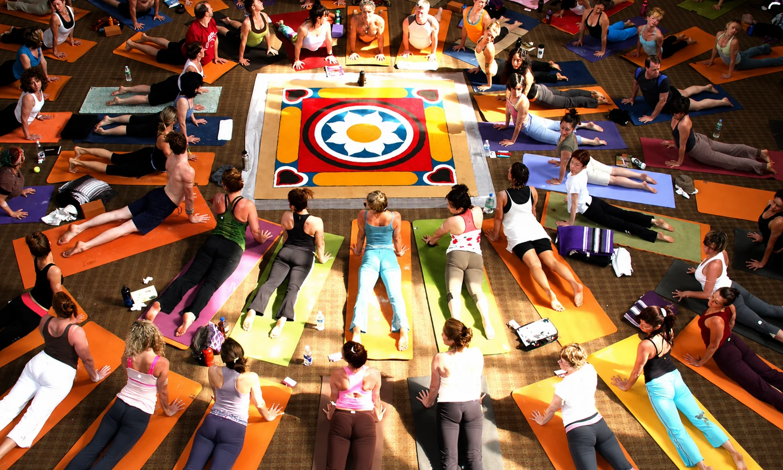A circle of practitioners moving around a colourful mandala